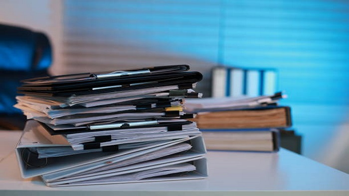une pile de dossiers administratifs sur une table de bureau - gérer les tâches administratives médicales - Serenity
