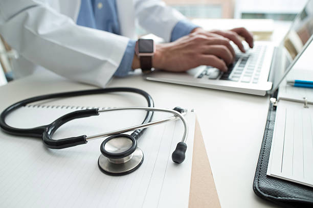 un médecin tapant sur les claviers d'un laptop - télésecrétariat pour les établissements de santé - Serenity