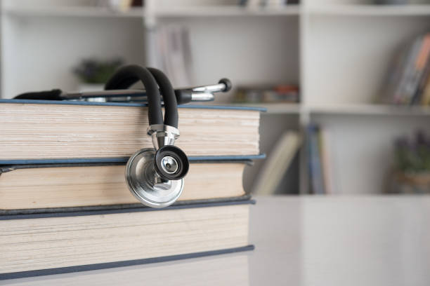 stéthoscope sur une pile de livres médicaux sur le bureau d'un médecin - formatrice en centre d'appels médical - Serenity