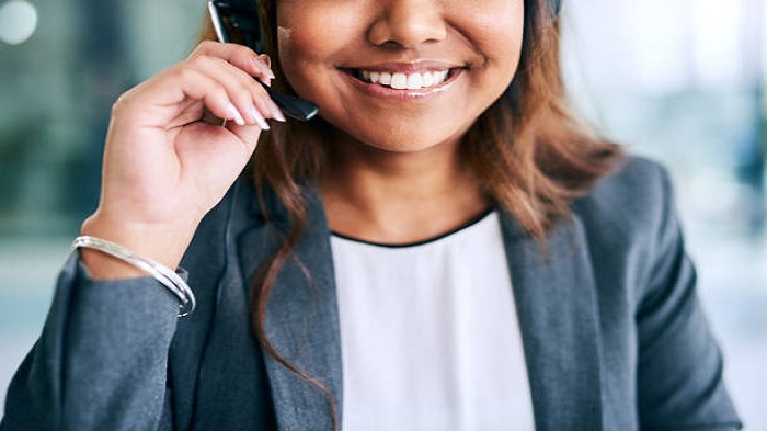 Photo recadrée d'une jeune femme souriante utilisant un casque - accueil téléphonique en centre d’appels - Serenity
