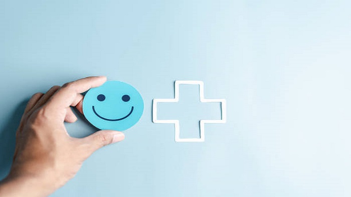 Les mains tenant un visage bleu et souriant pour les soins médicaux - externalisation du standard téléphonique - Serenity