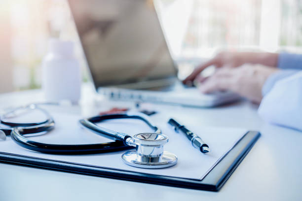 Le stéthoscope, le presse-papier et l'ordinateur portable sont posés sur le bureau d'un médecin - externaliser le secrétariat médical - Serenity